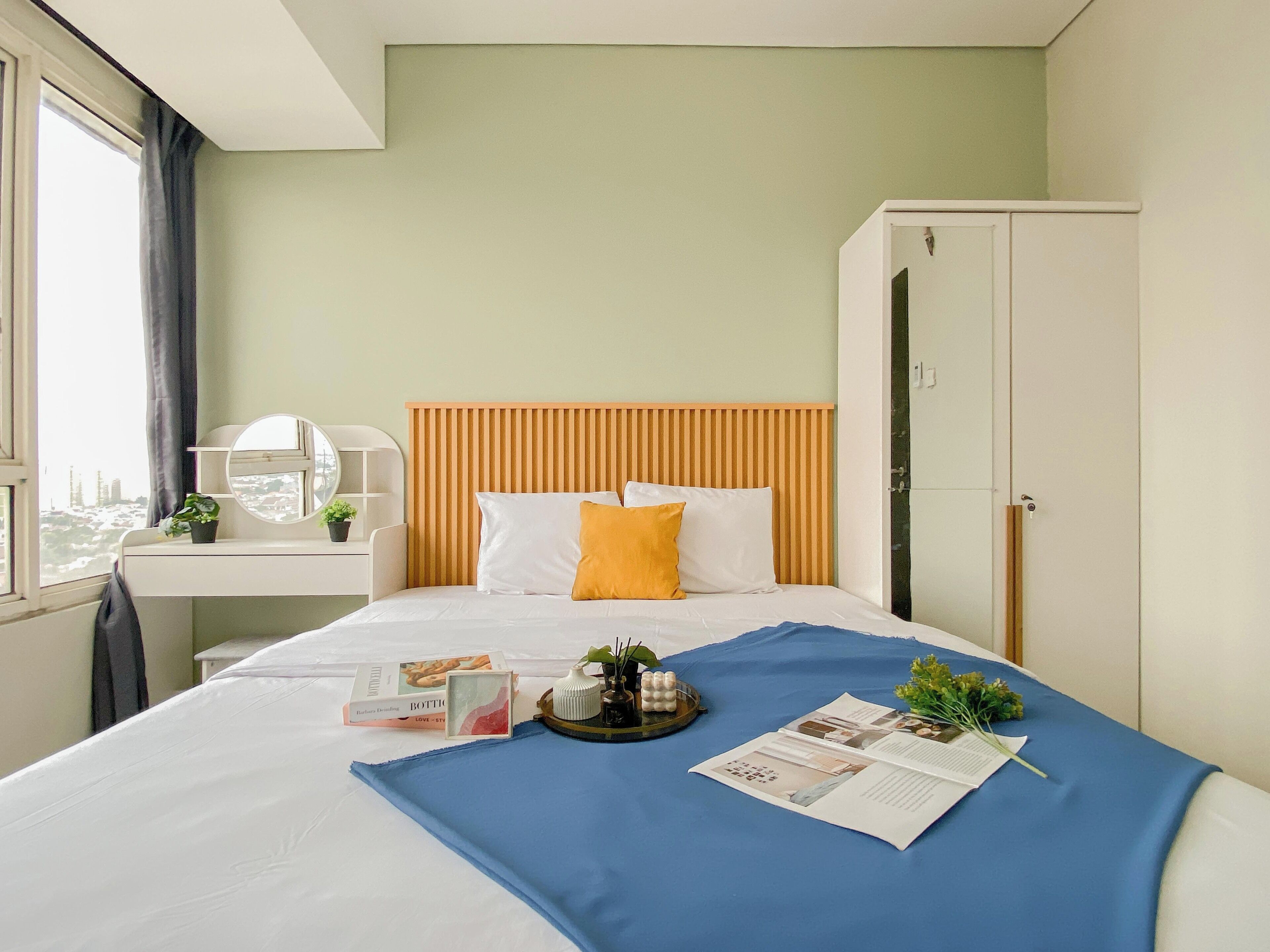 A hotel room with a bed, a bedside table with a lamp, a window with curtains, and a wardrobe.
