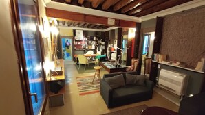 Un accogliente soggiorno con un divano scuro, un tavolino da caffè e un camino. C'è una libreria piena di libri e un'area pranzo con tavolo e sedie.