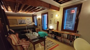 Un accogliente soggiorno con soffitto in legno, una scrivania con un portatile, una poltrona a righe e una libreria piena di raccoglitori.