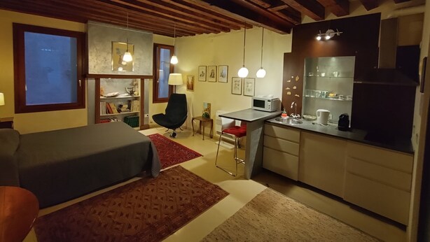 Una camera compatta con un letto, una scrivania e angolo cottura.