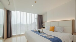 Una habitación de hotel moderna con una cama grande, una mesita de noche y un ventanal con cortinas.