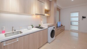 Una cocina moderna con armarios de madera, lavadora integrada y un amplio ventanal.