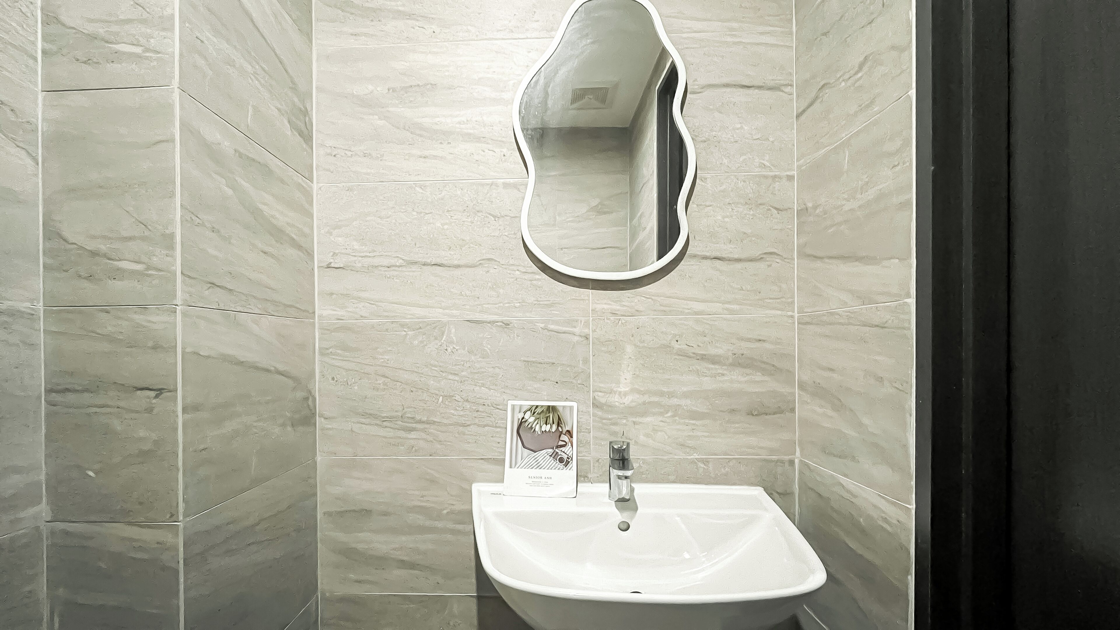 Un baño con un lavamanos blanco, un espejo y un cuadro en la pared.