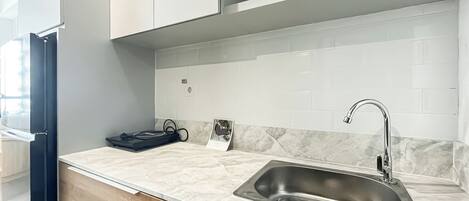 A modern kitchen with a stainless steel sink, white subway tiles, and wooden cabinets.