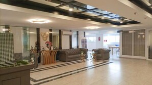 Eine geräumige Lobby mit Empfangsschalter, Sitzgelegenheiten und einer Glastrennwand.