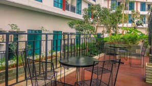 A courtyard with outdoor seating, surrounded by a metal fence, and a building with multiple balconies in the background. - Modern Style Studio At Apartment Lrt City Bekasi (Bekasi)