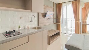 A modern kitchen with a built-in stove, a sink, and a wooden shelf. - Modern Style Studio At Apartment Lrt City Bekasi (Bekasi)