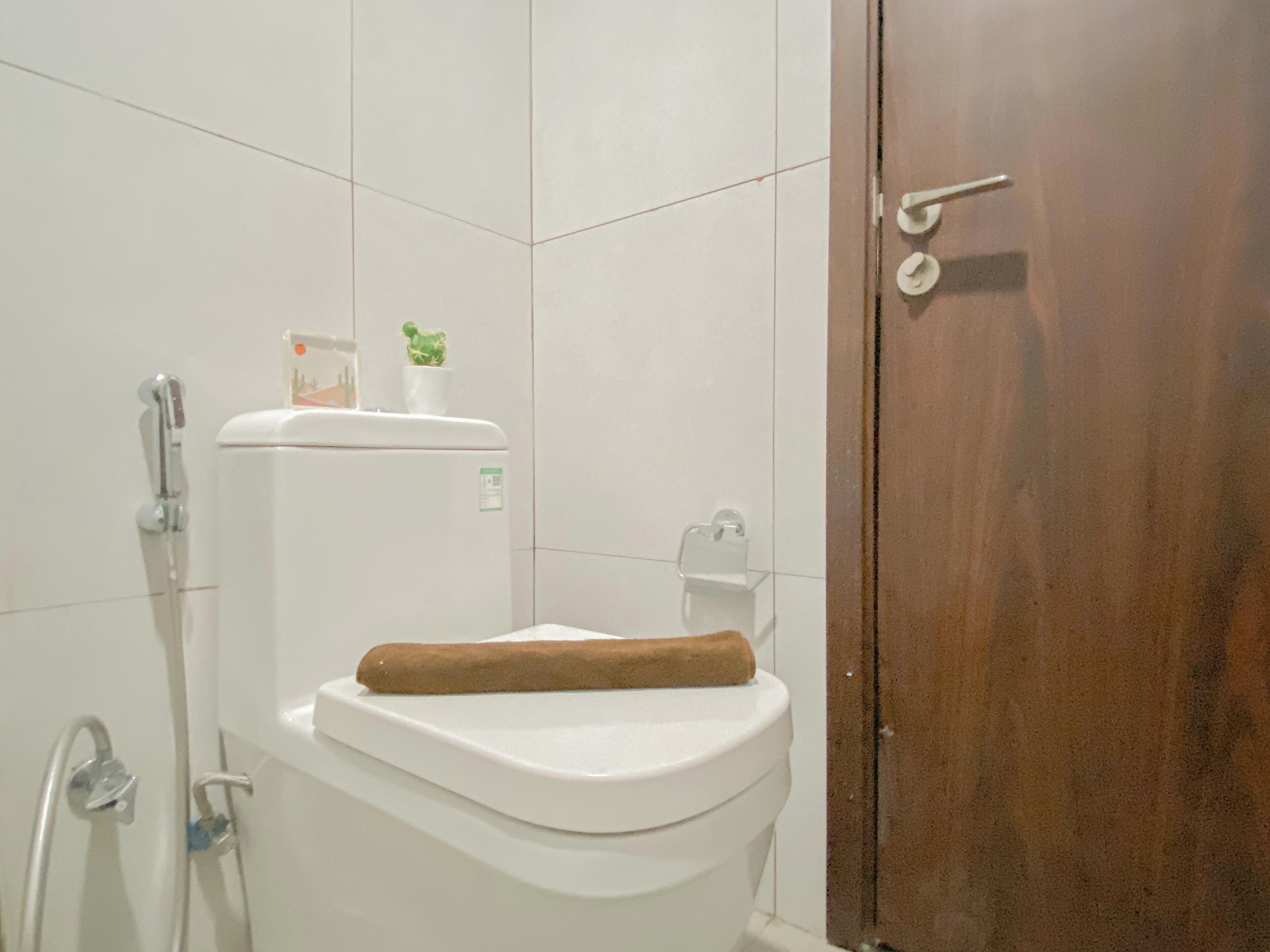 Un baño con inodoro blanco, ducha y puerta de madera.