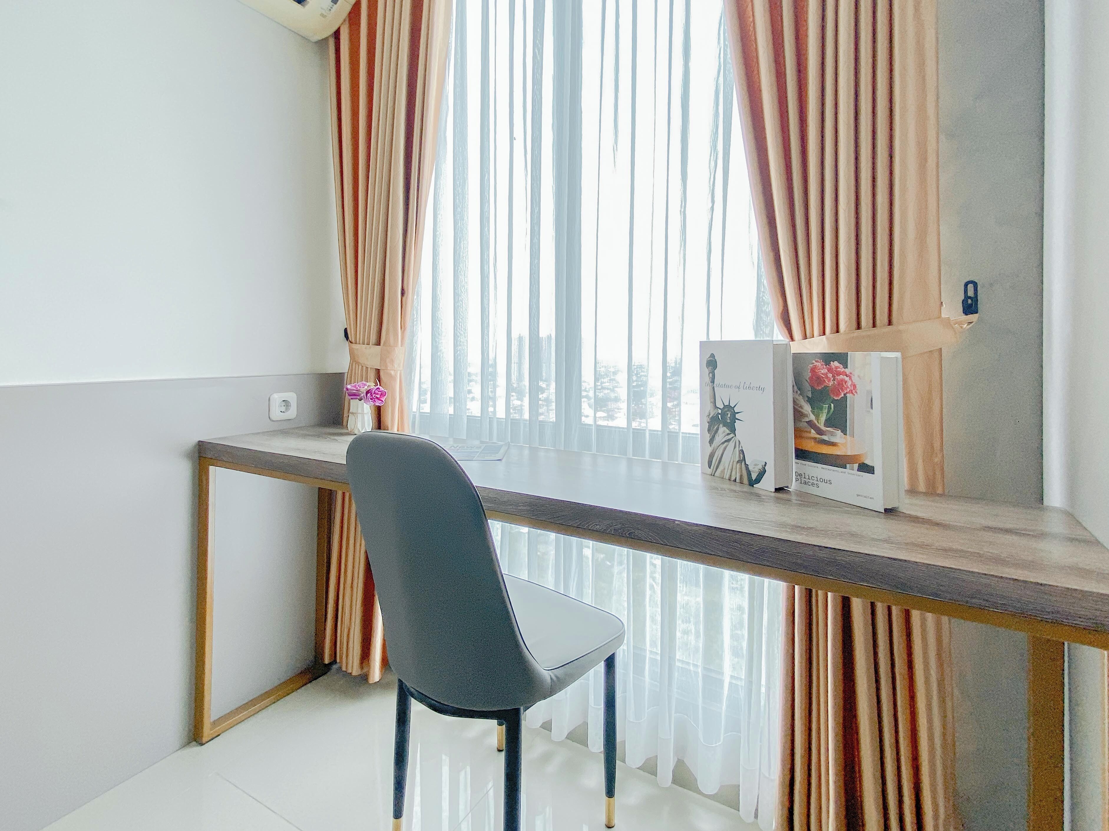A modern room with a desk, a chair, a window with curtains, and a framed picture of the Statue of Liberty.