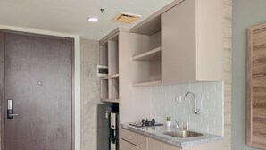 A modern kitchen with a built-in refrigerator, a stainless steel sink, and a wooden door. - Modern Style Studio At Apartment Lrt City Bekasi (Bekasi)