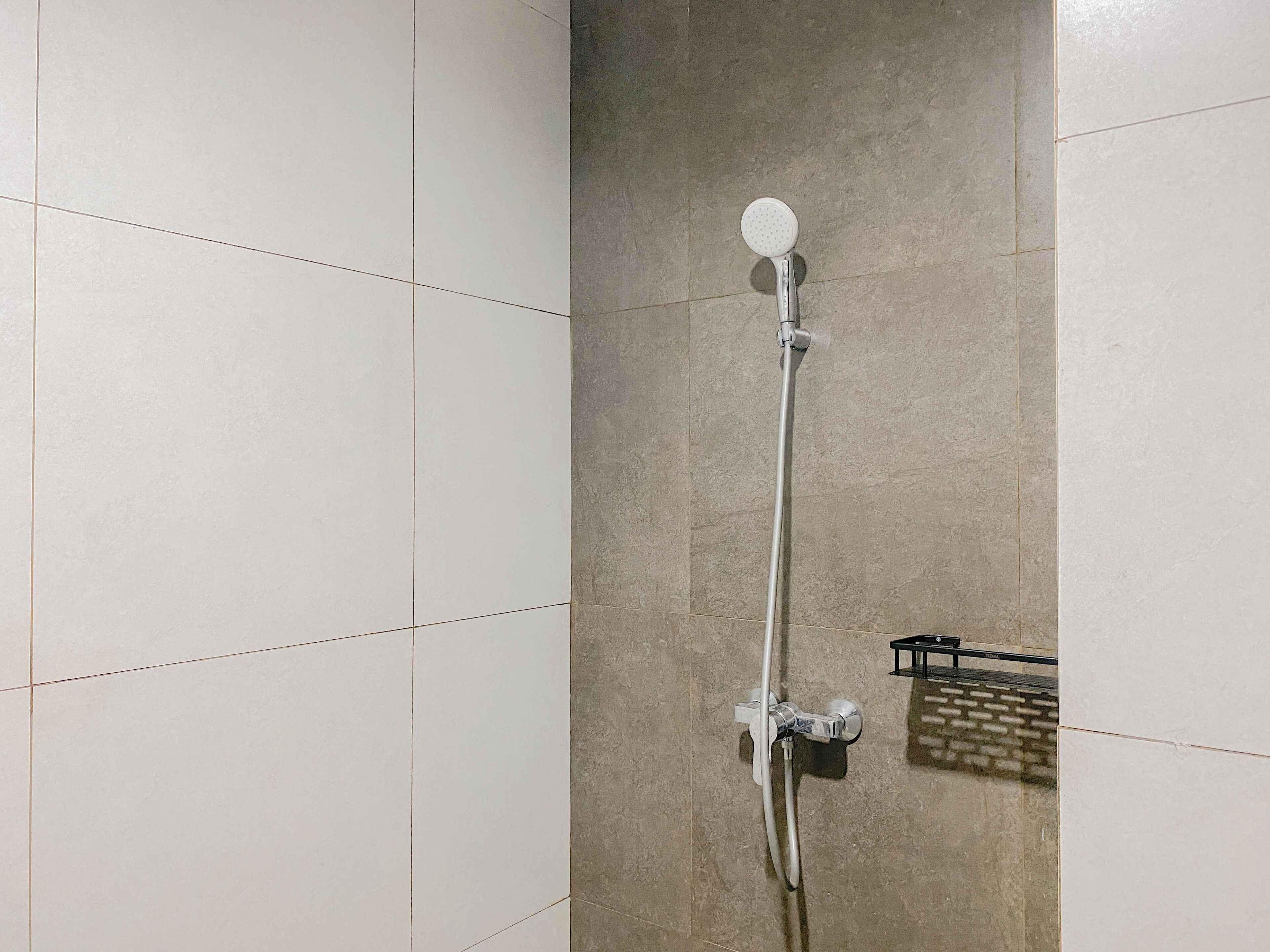 Een douche met een handdouche en een kraan op de muur.