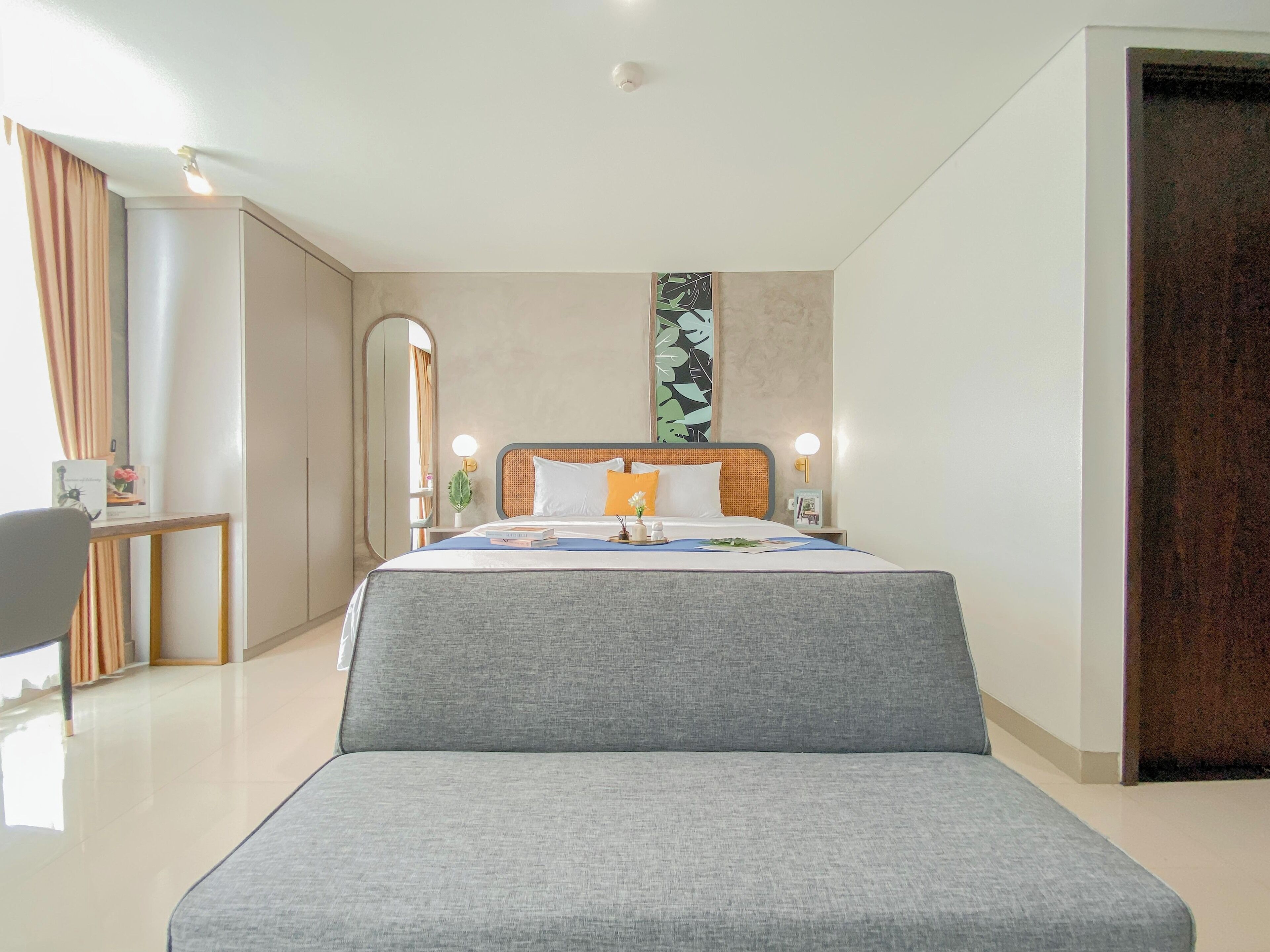 Ein modernes Hotelzimmer mit einem großen Bett, einem Schreibtisch und einem Spiegel.