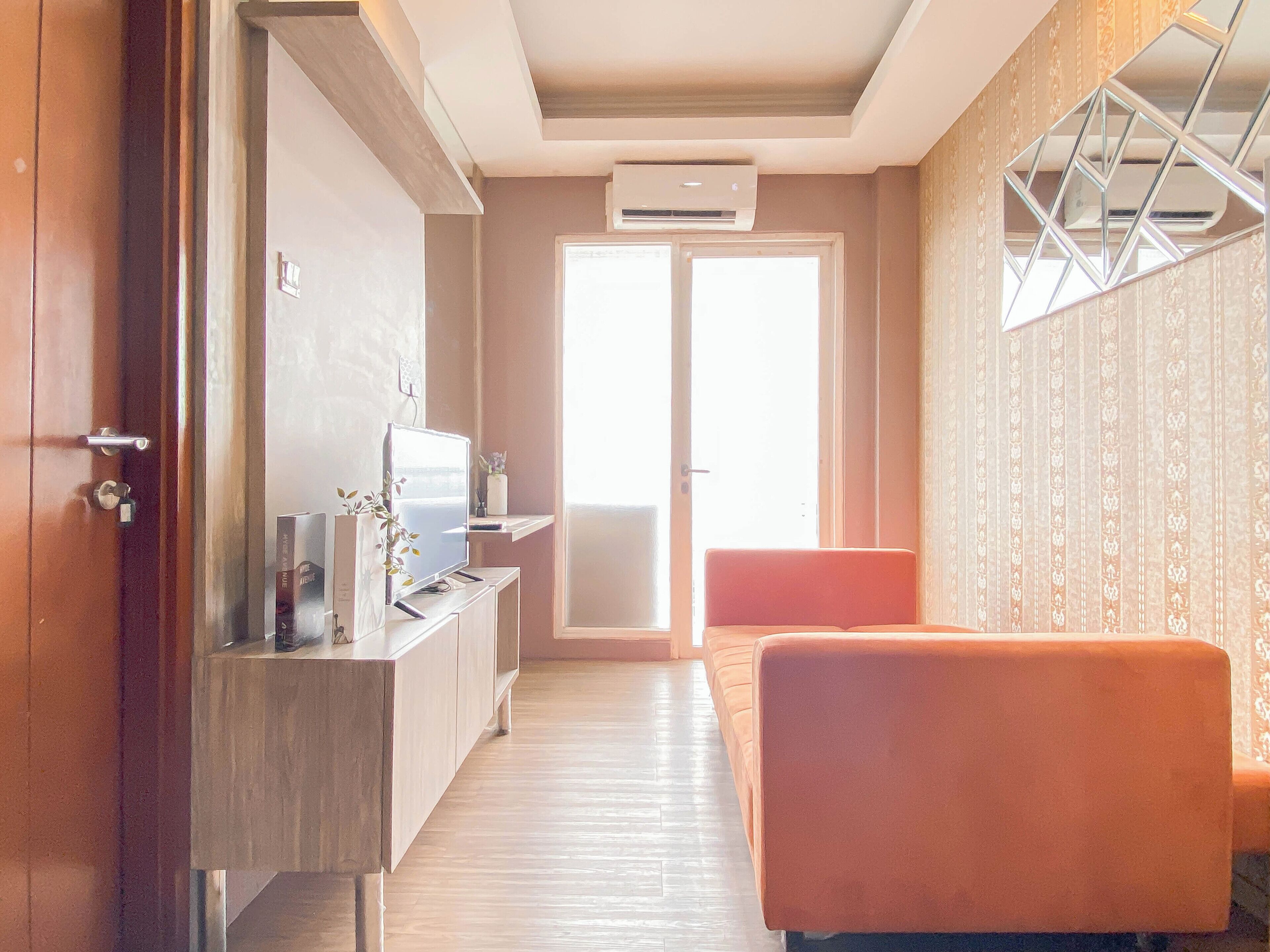 Une chambre d’hôtel avec un bureau en bois, une télévision, un canapé et une grande fenêtre donnant sur un beau paysage.