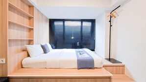 Une chambre à coucher moderne avec un lit en bois, des étagères intégrées, une table de chevet et une lampe sur pied.