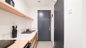 Une cuisine de taille réduite, dotée d’une porte sombre, d’un plan de travail en bois et d’un lave-vaisselle encastré.