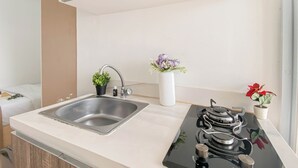 A modern kitchen with a stainless steel sink, a gas stove, and two potted plants. - Basic Studio Apartment At Vittoria Residence (Jakarta)