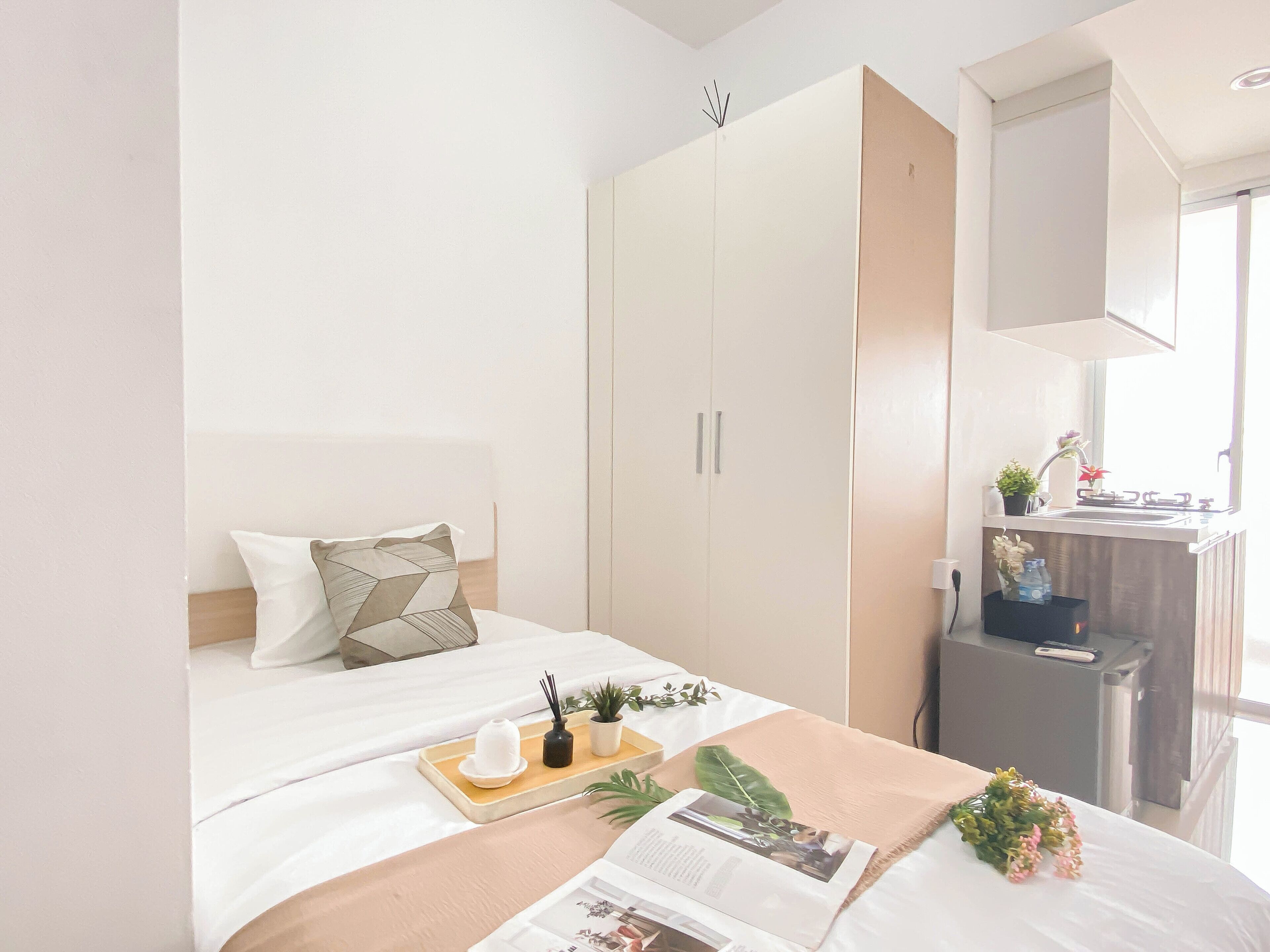 A modern hotel room with a bed, a bedside table, a wardrobe, and a window with a view.