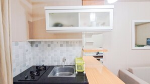 A compact kitchen with a gas stove, sink, and a small countertop. - Standard 2Br At Parahyangan Residence Apartment (Bandung)