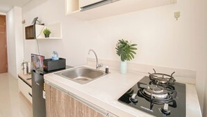 A modern kitchen with a stainless steel sink, a gas stove, and a potted plant. - Ivory Nest 1Br At Vittoria Residence Apartment (Jakarta)