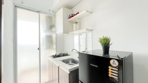 Una cocina compacta con un refrigerador negro, un lavamanos y una pequeña encimera.