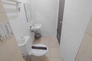 Een kleine, functionele badkamer met toilet, wastafel en spiegel.