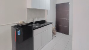 Una cocina compacta con un refrigerador negro, un lavamanos y un armario.
