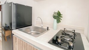 Una cocina moderna con un refrigerador negro, un lavamanos de acero inoxidable, una estufa a gas y una planta en maceta.