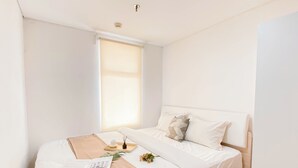 Un dormitorio ordenado con cama, mesita de noche y ventana.