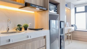 Eine moderne Küche mit einem Edelstahlkühlschrank, einem Einbauofen und einer Mikrowelle. Es gibt ein Waschbecken mit einem modernen Wasserhahn und einen Blumentopf auf der Arbeitsfläche.