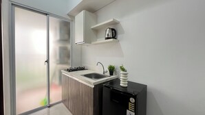 A modern kitchen with a built-in sink, a stove, and a coffee maker on a shelf. - Restful 2Br At Vittoria Residence Apartment (Jakarta)