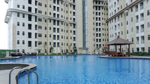 A swimming pool with a gazebo, lounge chairs, and a high-rise building in the background. - Restful 2Br At Vittoria Residence Apartment (Jakarta)