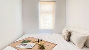 A neatly made bed with a beige blanket, a tray with a plant, and a magazine on the bed. - Convenient 1Br Apartment At Vittoria Residence (Jakarta)