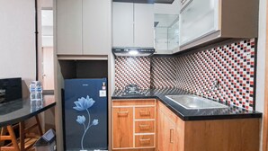 A compact kitchen with a refrigerator, sink, and wooden cabinets. - Well Furnished 2Br At Apartment Suites @Metro (Bandung)