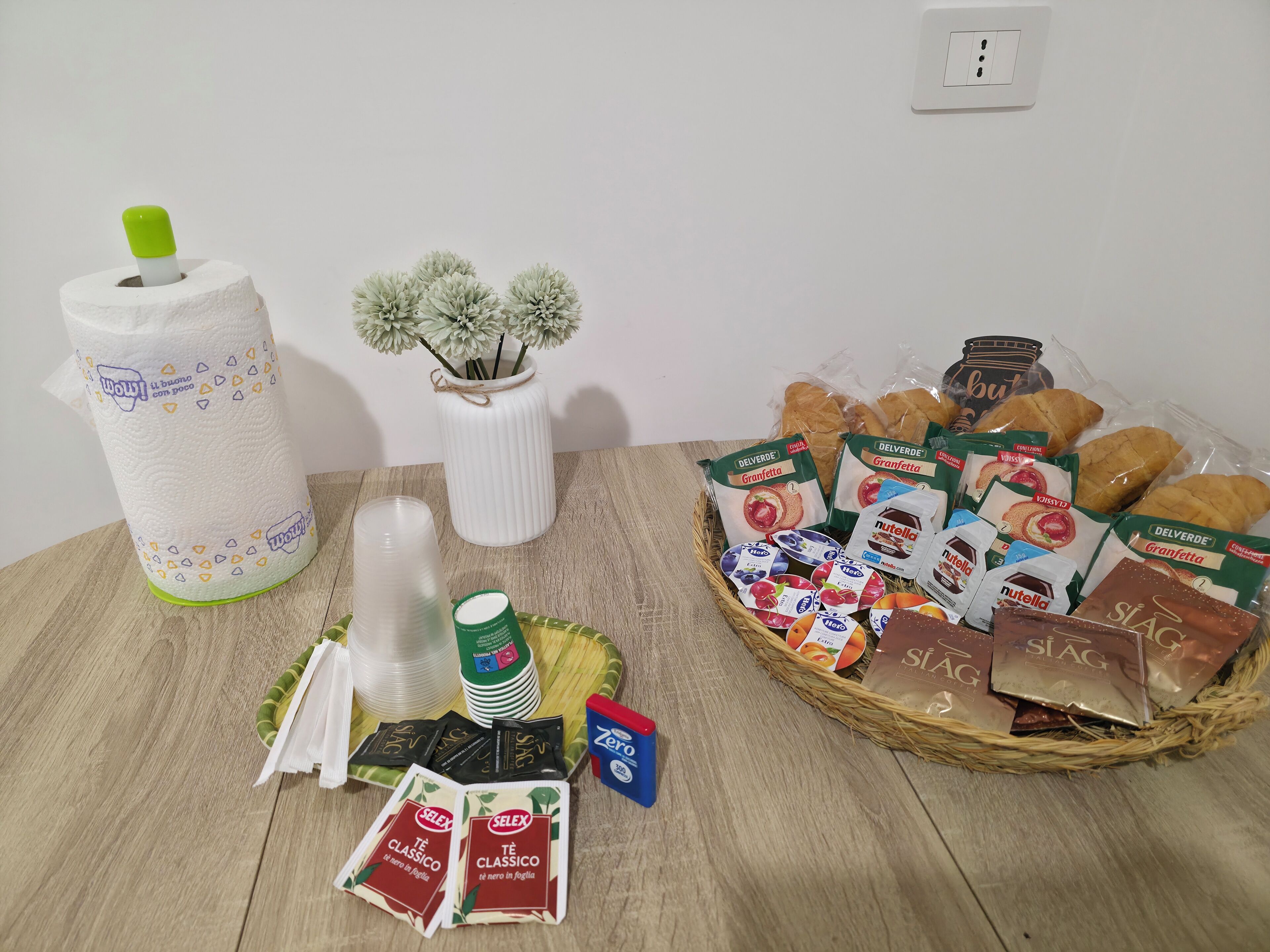 Une table sur laquelle on trouve divers aliments, notamment des en-cas emballés, du pain et un panier de viennoiseries.