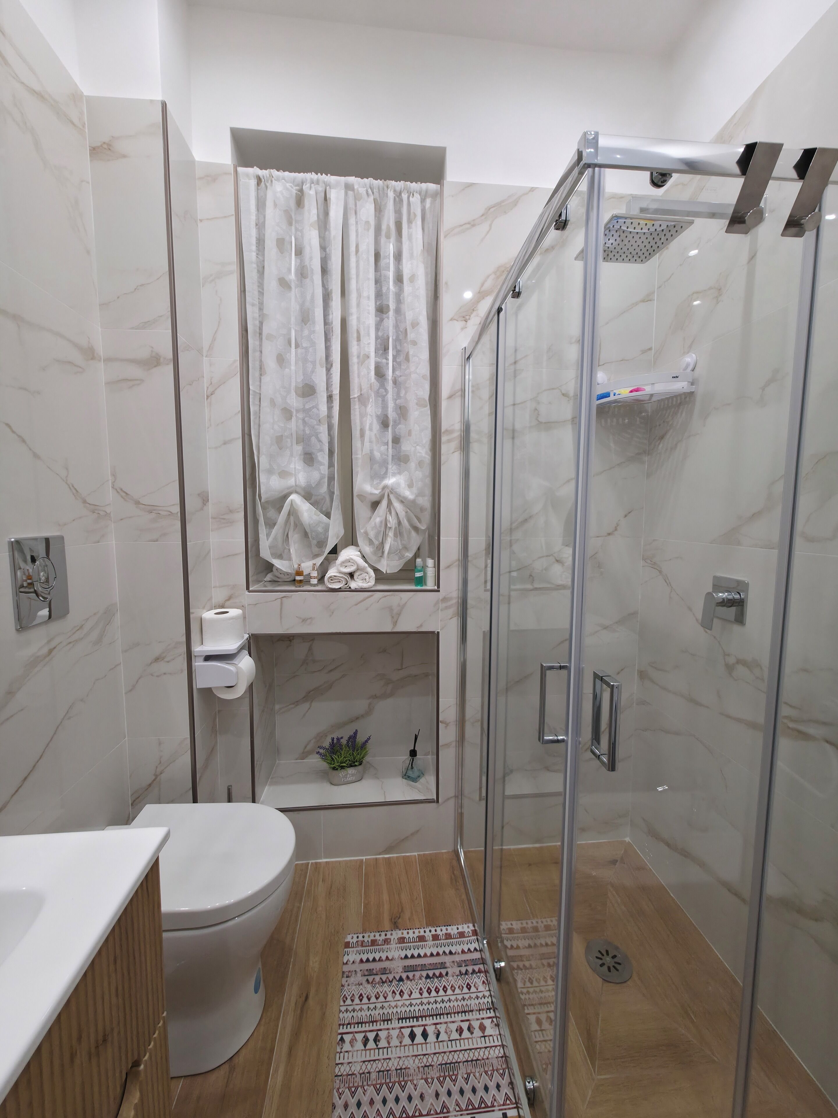 Un bagno moderno con servizi igienici, doccia e un piccolo ripiano con articoli da toilette.