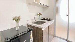 A compact kitchen with a sink, a stove, and a small refrigerator. - Trendy 1Br At Apartment Vittoria Residence (Jakarta)