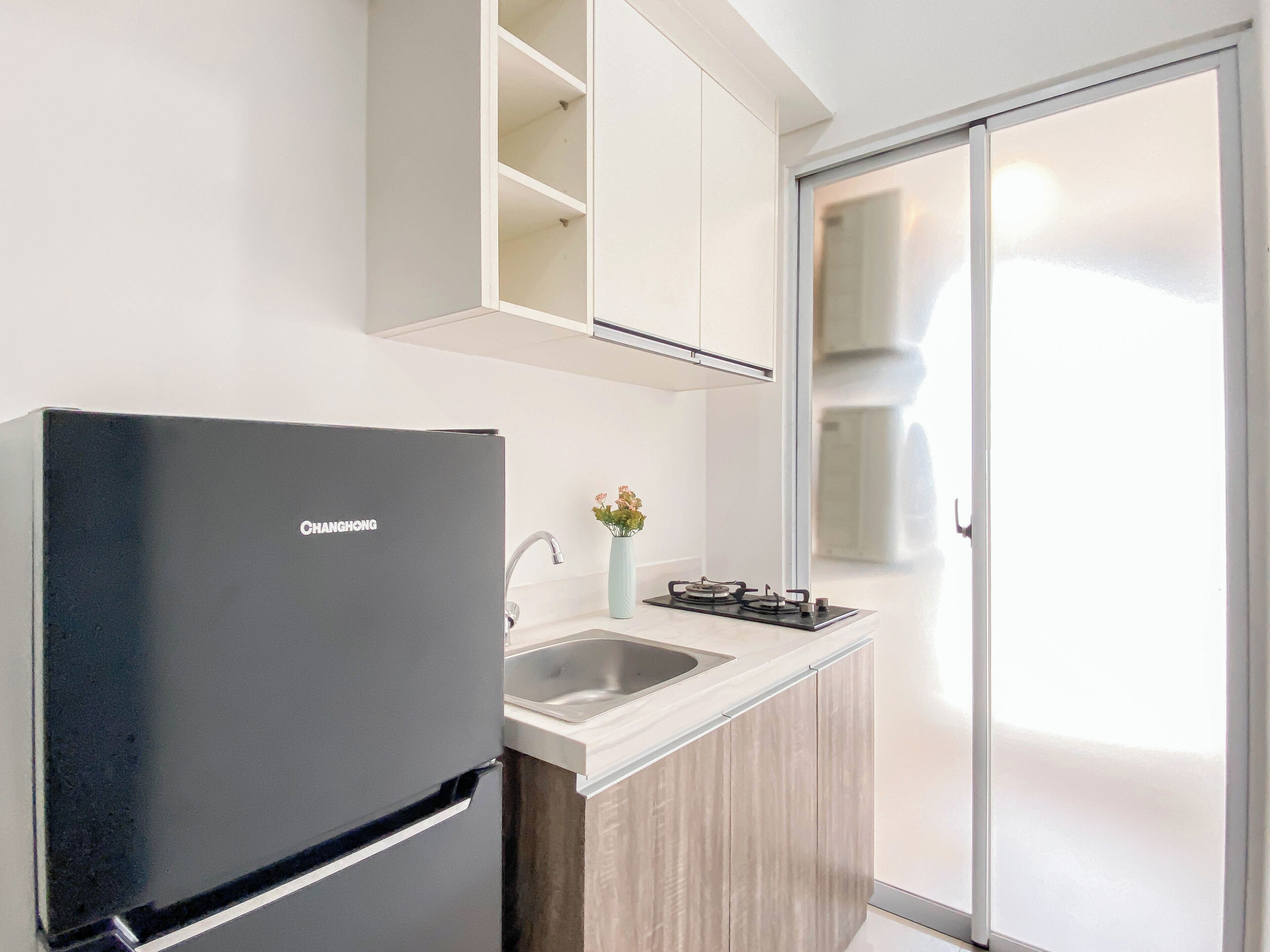 Una cocina moderna con un refrigerador negro, un lavamanos y una estufa a gas.