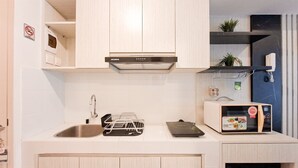 A modern kitchen with a stainless steel sink, a built-in oven, and a microwave on the countertop. - Minimalist And Restful Studio At Tokyo Riverside Pik 2 Apartment (Teluknaga)