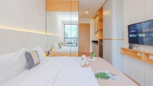 Une chambre d’hôtel moderne, dotée d’un grand lit, d’une télévision, d’un miroir et offrant une vue sur la ville par la fenêtre.