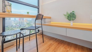Un espace de bureau moderne avec une grande fenêtre, un bureau en bois, une chaise noire et une plante en pot.