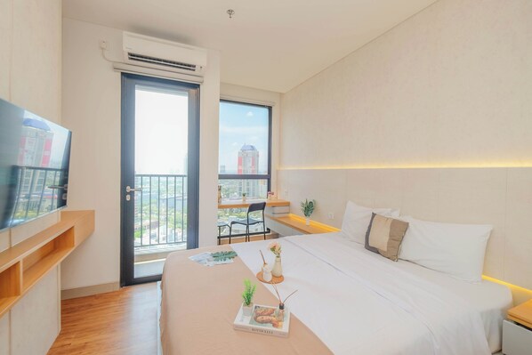 A modern hotel room with a large bed, bedside table, and a TV on a stand. - Standard Studio At Apartment Ciputra World 2 (Jakarta)