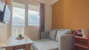 Ein kleiner, kompakter Raum mit einer Couch, einem Tisch und einem an der Wand montierten Fernseher.