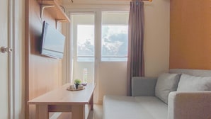 Ein kleiner, kompakter Raum mit einem Bett, einem Tisch mit Pflanze und einem an der Wand befestigten Fernseher.