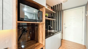 A compact kitchen with a microwave, oven, and sink. - Cozy Stay Studio Apartment At M-Town Residence (Gading Serpong)