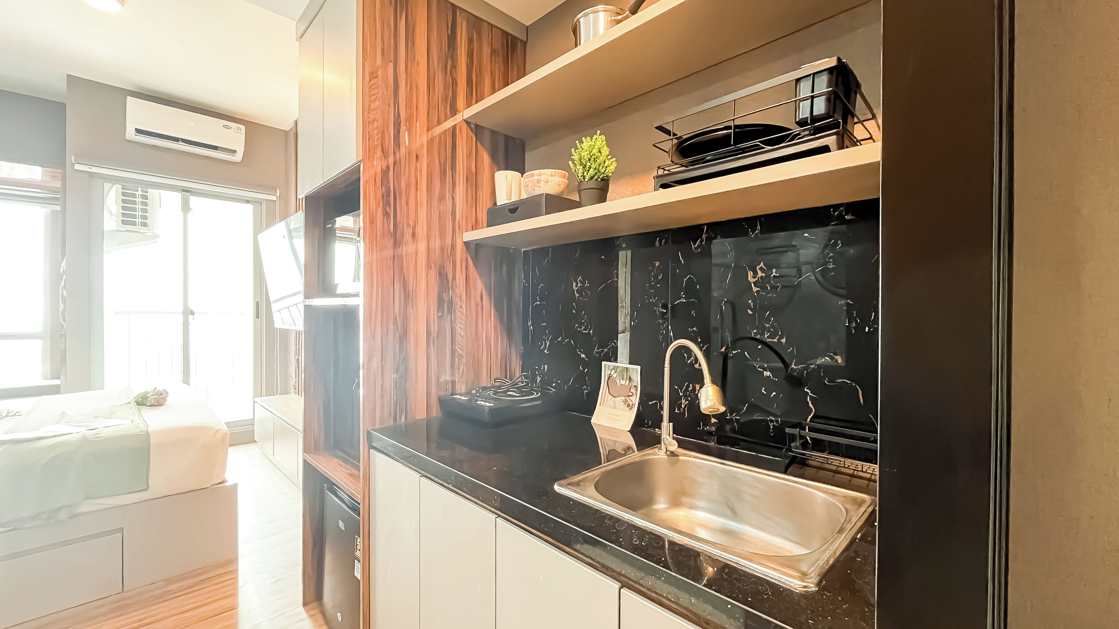 A modern kitchen with a black marble backsplash, stainless steel sink, and wooden panel accents.