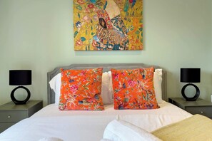 A bed with two pillows, a bedside table with a lamp, and a wall-mounted painting. - Elegant Shoreditch Apartment with Private Balcony (Greater London)