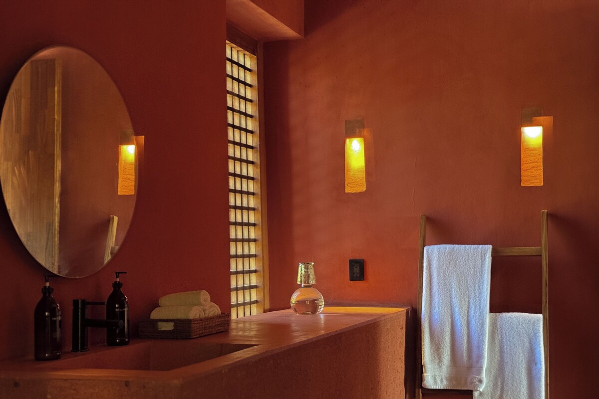 A bathroom with a large mirror, a sink, and two wall-mounted lights.