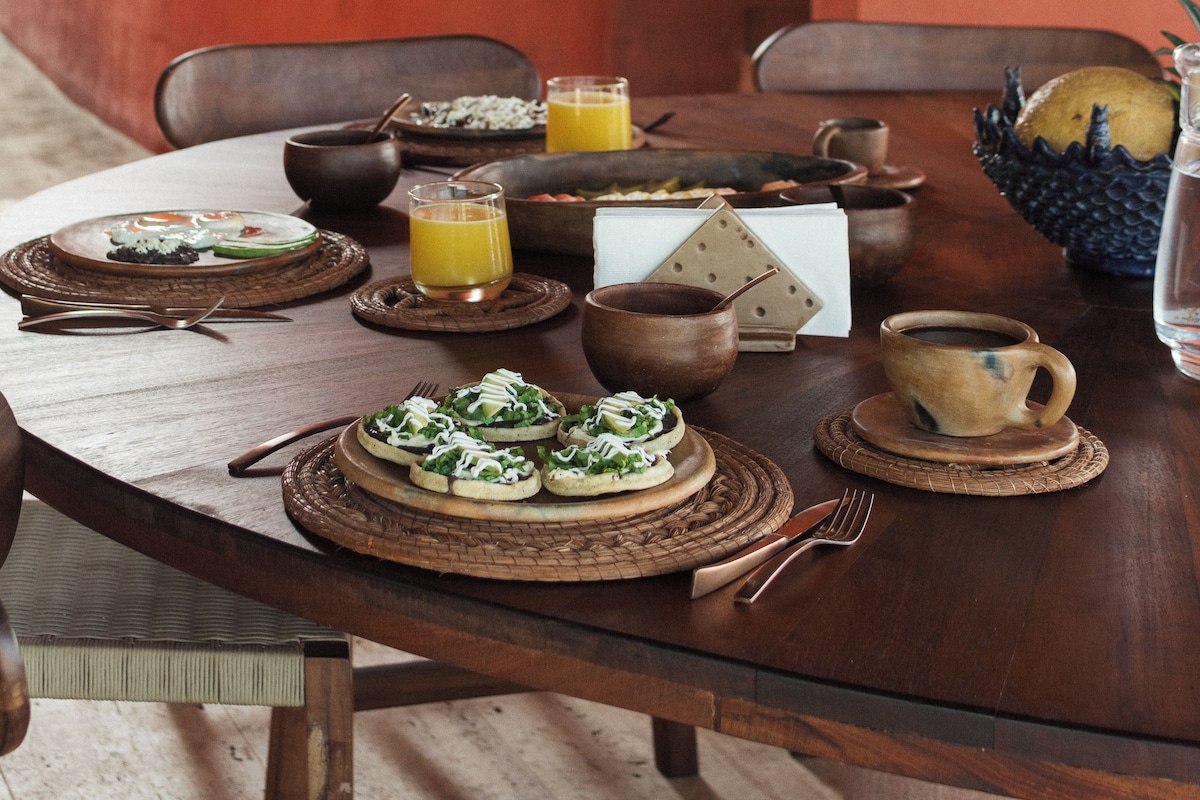 A dining table set with plates, bowls, and glasses, surrounded by chairs.