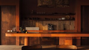 Una cocina moderna con una amplia mesa de madera, una cafetera y una lámpara de mimbre.