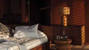 Un dormitorio con cama, mesita de noche y ventana con vistas al exterior.